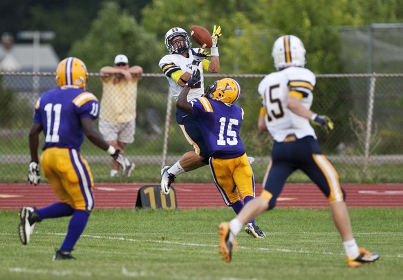 Saline senior running back Gage Hammond jumps to compete for a pass against Ypsilanti defender Tyree Weatherspoon on Friday. The Saline Hornets defeated Ypsilanti 49-14. Daniel Brenner I AnnArbor.com